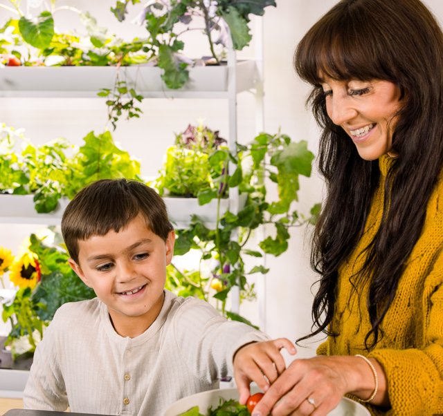 Mother and son making a healthy salad with produce harvested from their hydroponic tower garden. The Rise gardens allows you to grow tomatoes, eggplants, peppers and strawberries year-round right in your kitchen.