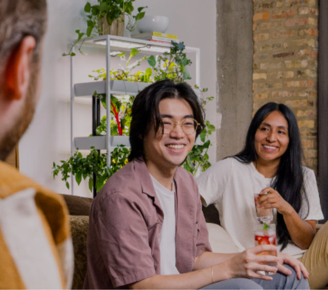 Friends gathered in front of hydroponic garden while they are having drinks with fresh strawberries and mint